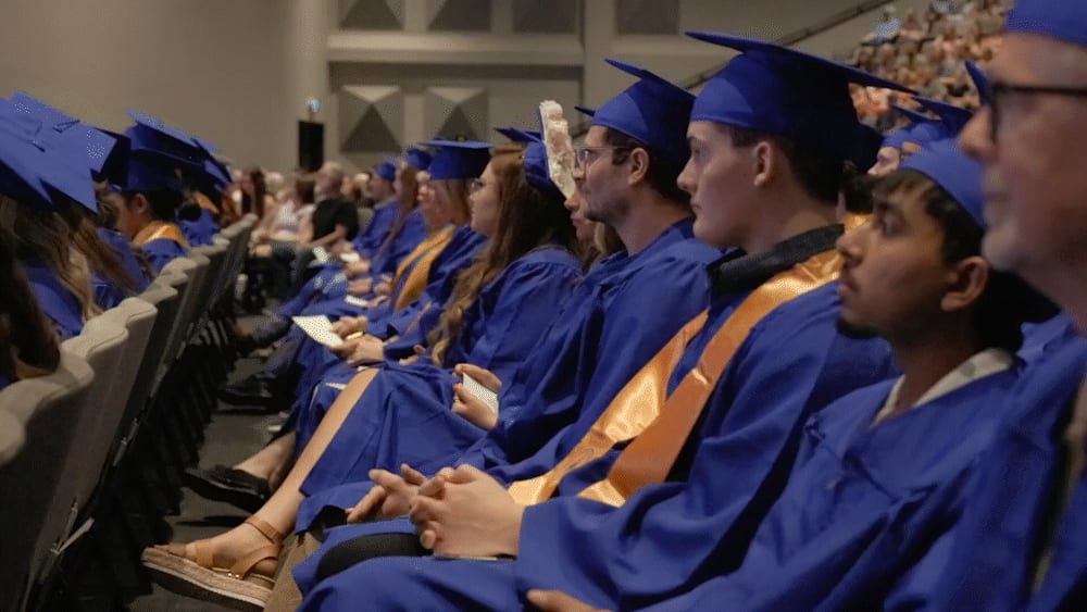 ECTC graduates in blue caps and gowns seated during a commencement ceremony